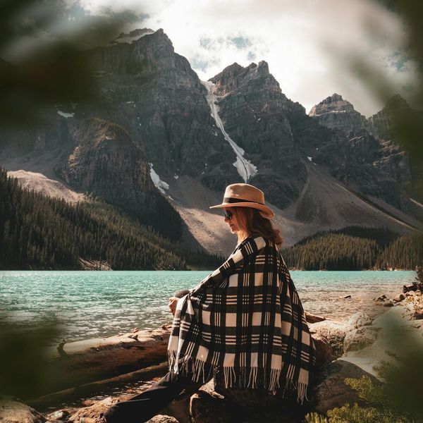 A person meditating peacefully outdoors near a calm lake.